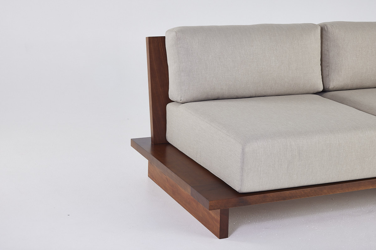 Custom designed couch design with timber frame and thick grey upholstery pillows.